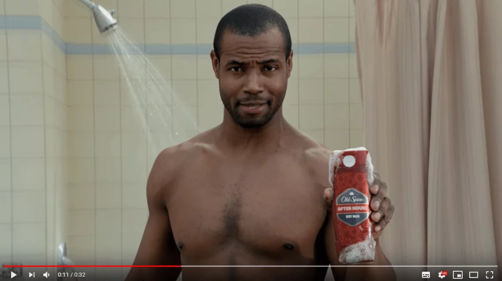 Кадр из рекламы Old Spice: мужчина в душе держит флакон геля для душа Old Spice и смотрит в камеру.