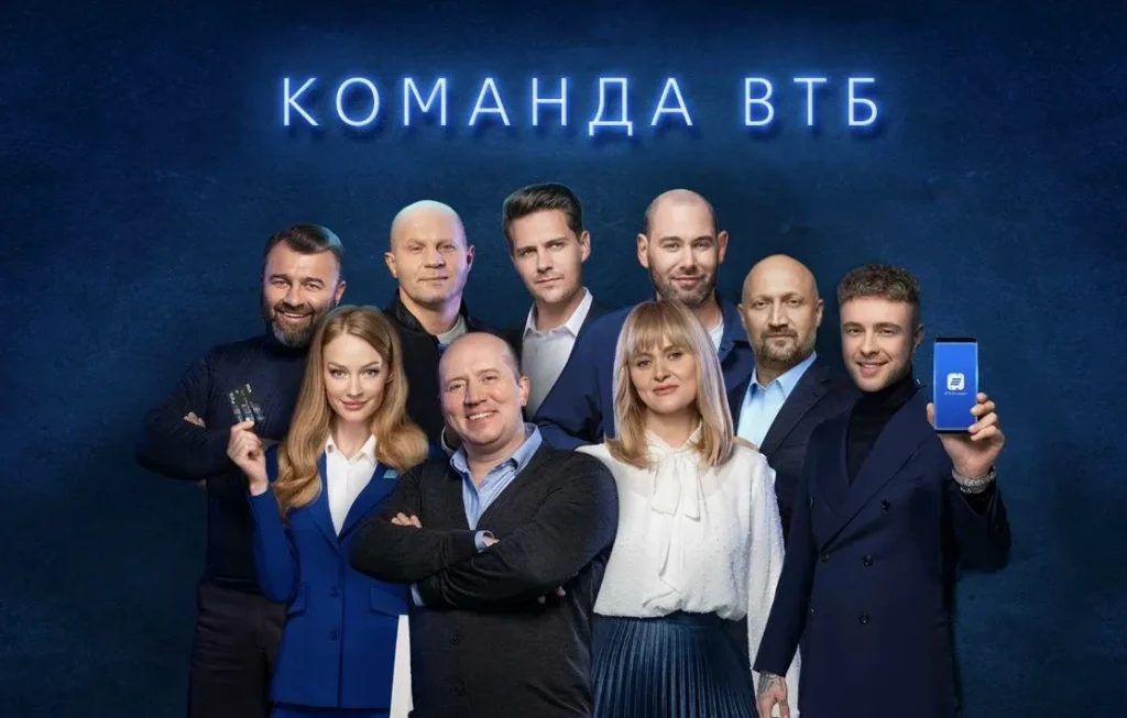 Группа людей позируют на синем фоне с надписью Команда ВТБ